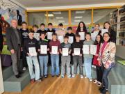 Direktor Mag. Nikolaus Stelzer (links) und Prof. Mag. Eva-Maria Gattringer (rechts) mit den Schülerinnen und Schülern, die ihre Zertifikate in Empfang genommen haben.